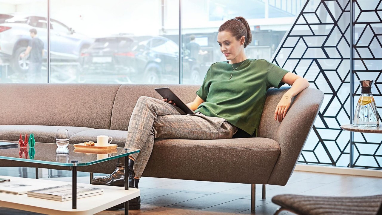 A woman sitting on a sofa in a Lexus dealership